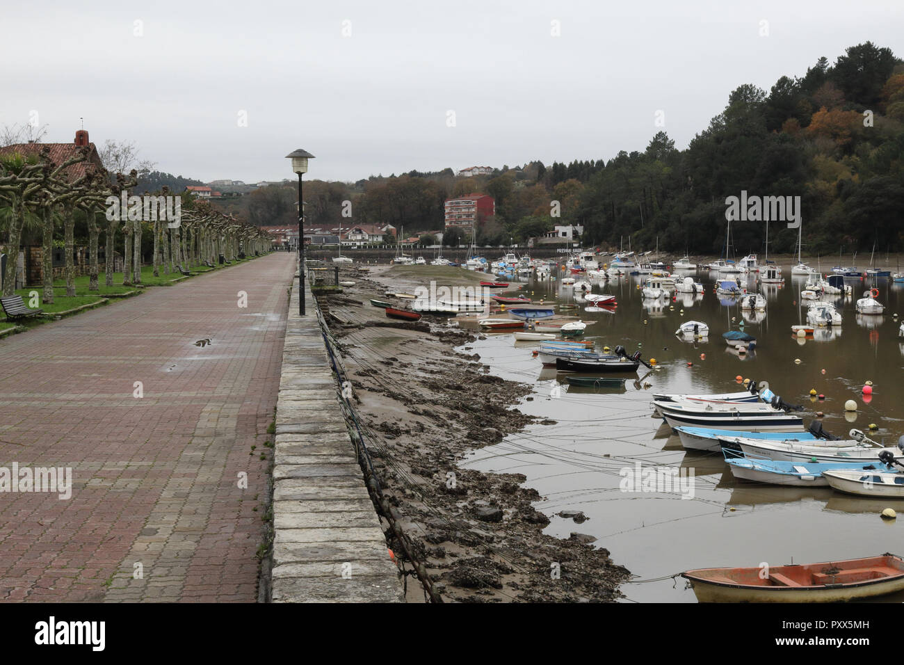 Il ria hore di Plentzia, nei Paesi Baschi in Spagna durante un freddo inverno nuvoloso giorno, con la bassa marea e piccole imbarcazioni private sul fango Foto Stock