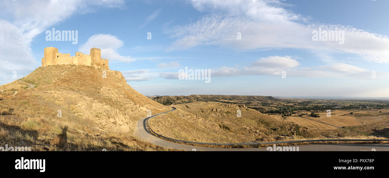 Un paesaggio del medievale abbandonato Montearagon castello posto su di una collina tra arati campi di raccolto, in un pomeriggio d'estate, nella regione di Aragona, Spagna Foto Stock