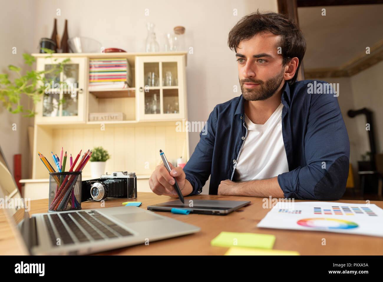 Graphic designer che lavora sulla tavoletta digitale. Libero professionista a lavorare a casa. Foto Stock