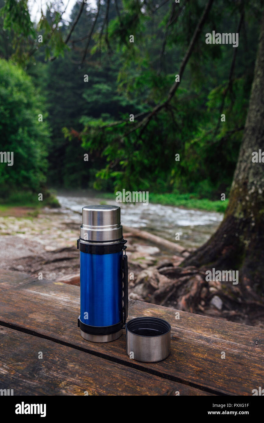 Vista sull'azzurro thermos sul tavolo di legno sul trekking. Pausa per una bevanda calda. Foto Stock