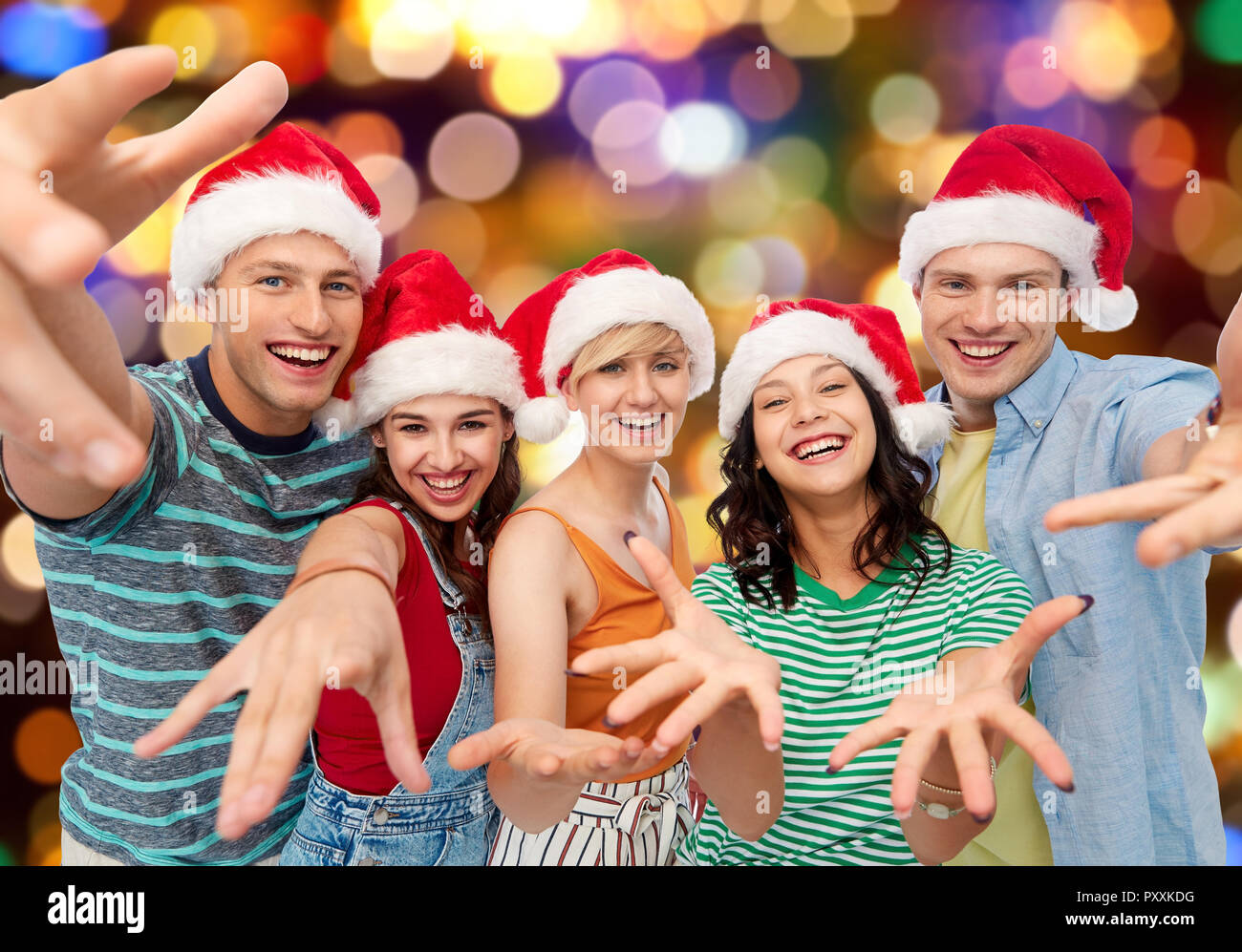 Happy amici in cappelli di Babbo Natale su luci festive Foto Stock