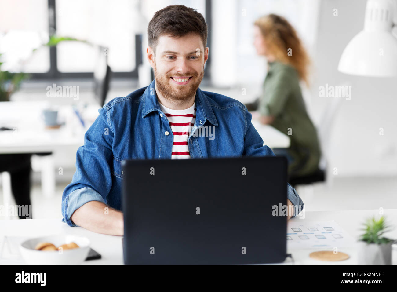 Sorridente uomo creativo con il computer portatile lavorando in ufficio Foto Stock