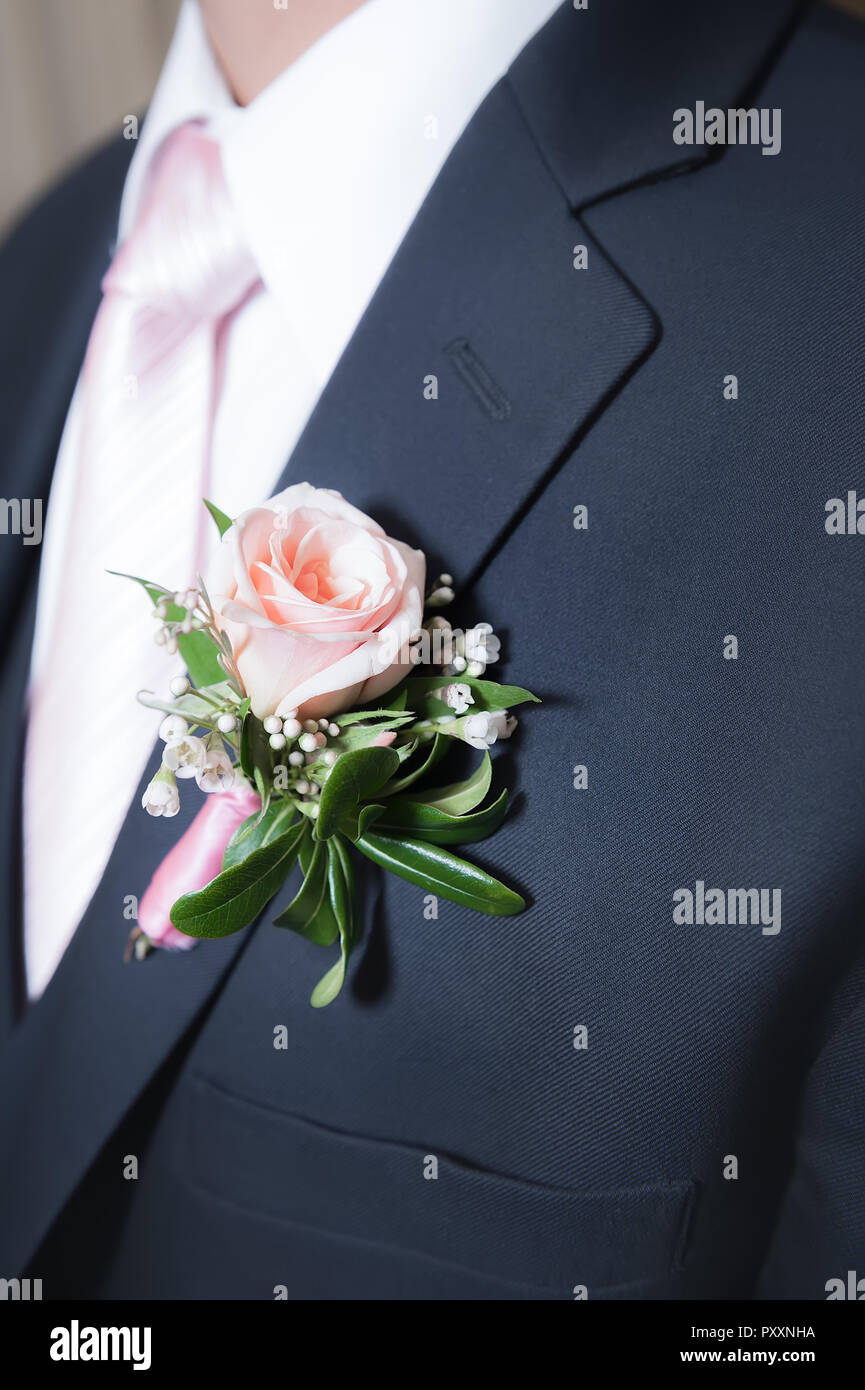 Una rosa rosa boutonniere su un uomo navy giacca. Foto Stock