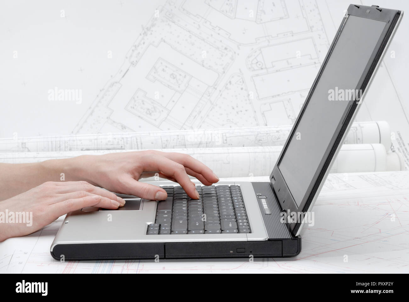 Mani femminili sulla tastiera del notebook. Piani architettonici in background. Foto Stock