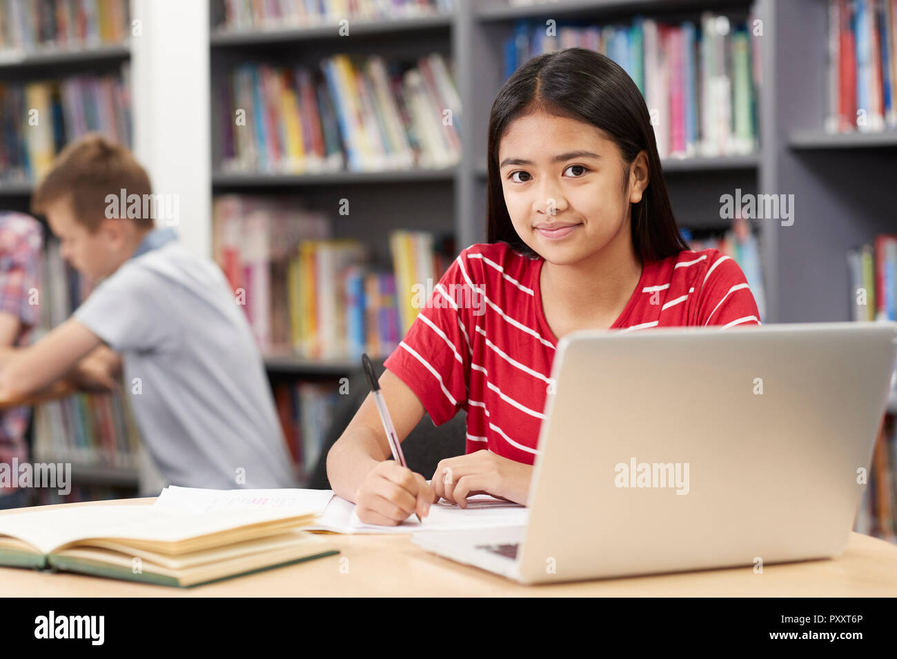 Ritratto di donna di alta scuola studente lavora al computer portatile in biblioteca Foto Stock
