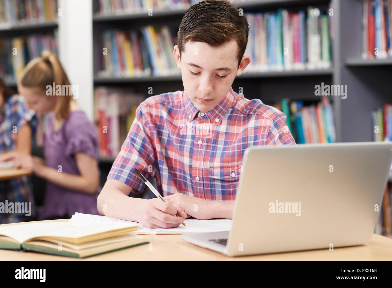 Maschio di alta scuola studente lavora al computer portatile in biblioteca Foto Stock