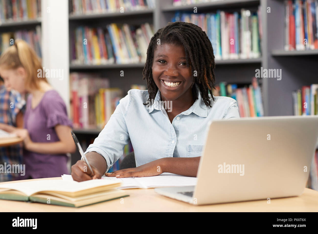 Ritratto di donna di alta scuola studente lavora al computer portatile in biblioteca Foto Stock