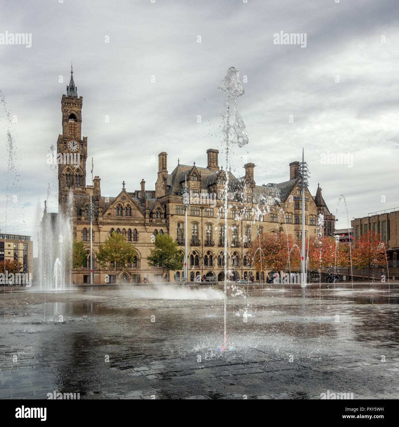 Bradford City Hall con fontane al centro della Piazza del Centenario piscina a specchio in una giornata autunnale con ricordo di papavero in alberi Foto Stock