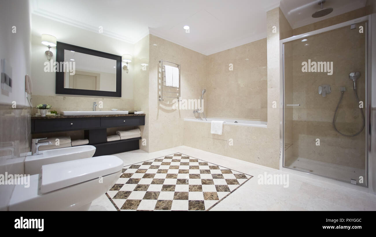 Un bel bagno in stile moderno con tonalità grigio pareti piastrellate. Vi è  una vasca da bagno di colore bianco con una parete di vetro, doccia,  specchi, luce lavabo, bidet e wc,