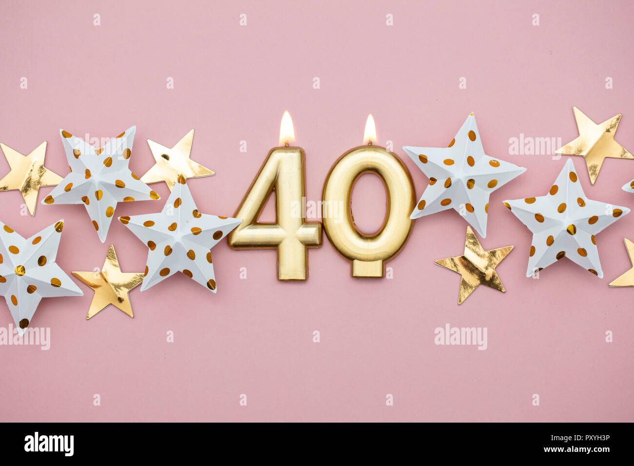 Numero 40 oro candela e stelle su un pastello sfondo rosa Foto Stock