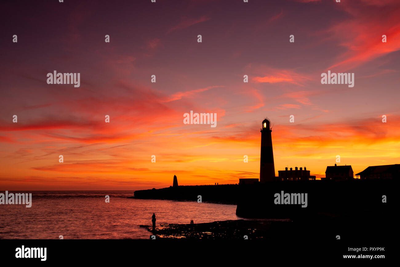 Portland, Dorset, Regno Unito. Il 24 ottobre 2018. Regno Unito Meteo: il famoso faro si stagliano contro i brillanti colori del tramonto a Portland su una bella serata autunnale. Credito: Celia McMahon/Alamy Live News Foto Stock