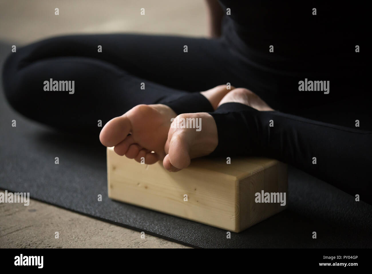 Yogi sportivo da donna a praticare yoga concetto, seduto in esercizio a farfalla, advanced baddha konasana pongono, utilizzando il blocco di legno, lavorando fuori, indossando spor Foto Stock