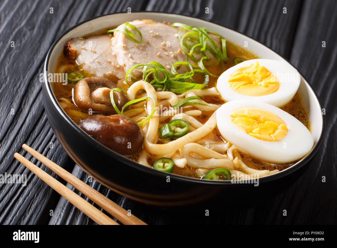 In stile asiatico con zuppa di udon noodles, maiale, uova sode, i funghi e le cipolle verdi close-up in una ciotola sul tavolo orizzontale. Foto Stock