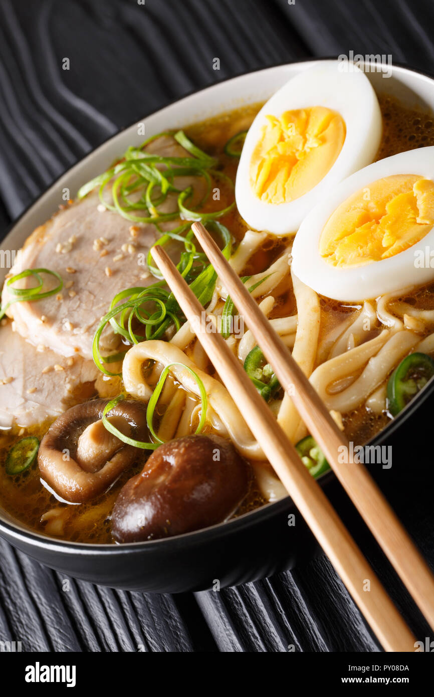 Deliziosa giapponese udon zuppa con carne di maiale, uova, shiitake e cipolle close-up in una ciotola sul piano verticale. Foto Stock