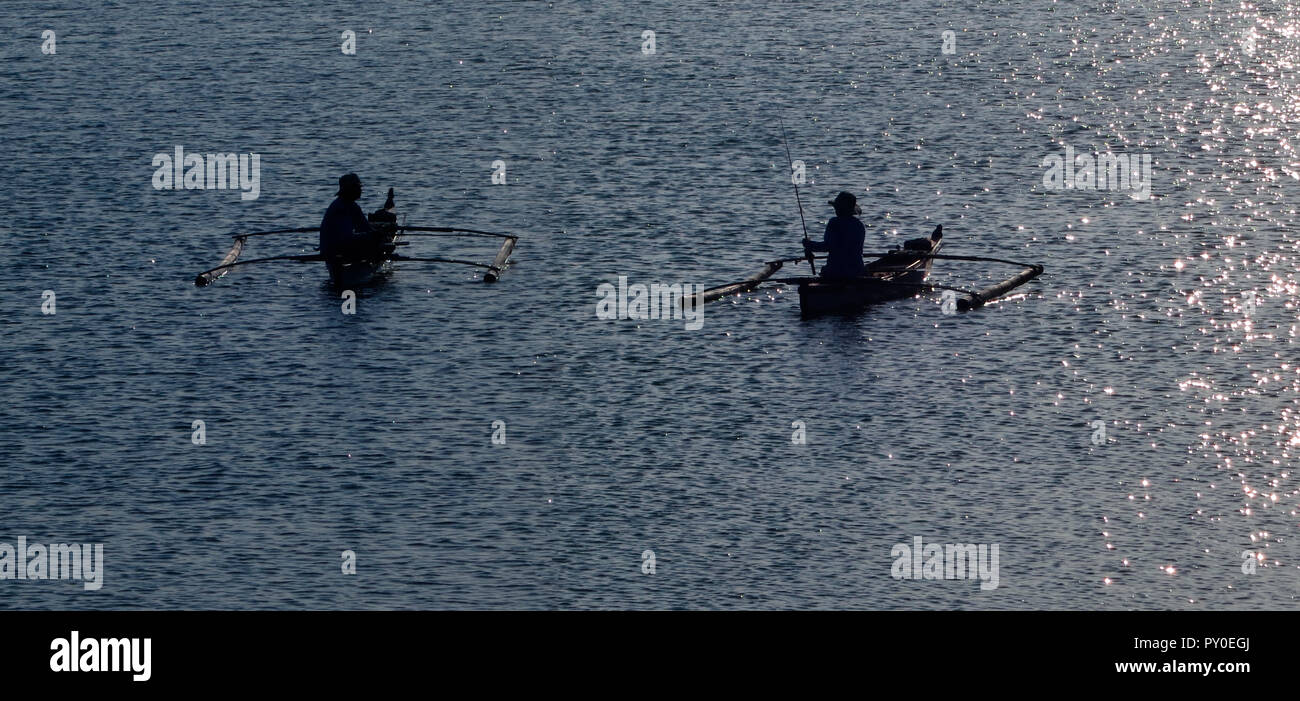 Sagome di due pescatori in outrigger barche, Baia di Manila, Filippine Foto Stock