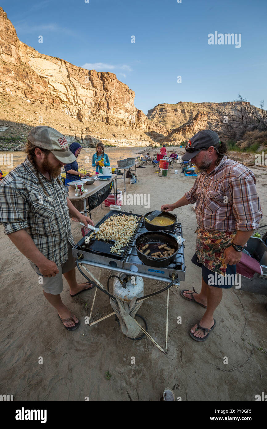 Due uomini pasto di cottura in cucina esterna durante il viaggio rafting, desolazione/Grigio sezione del canyon, Utah, Stati Uniti d'America Foto Stock