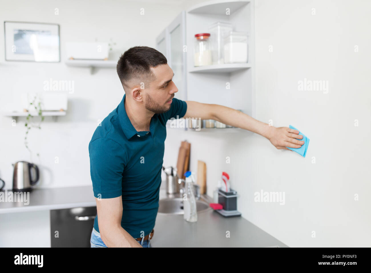 Uomo con uno straccio per la pulizia a parete cucina domestica Foto Stock