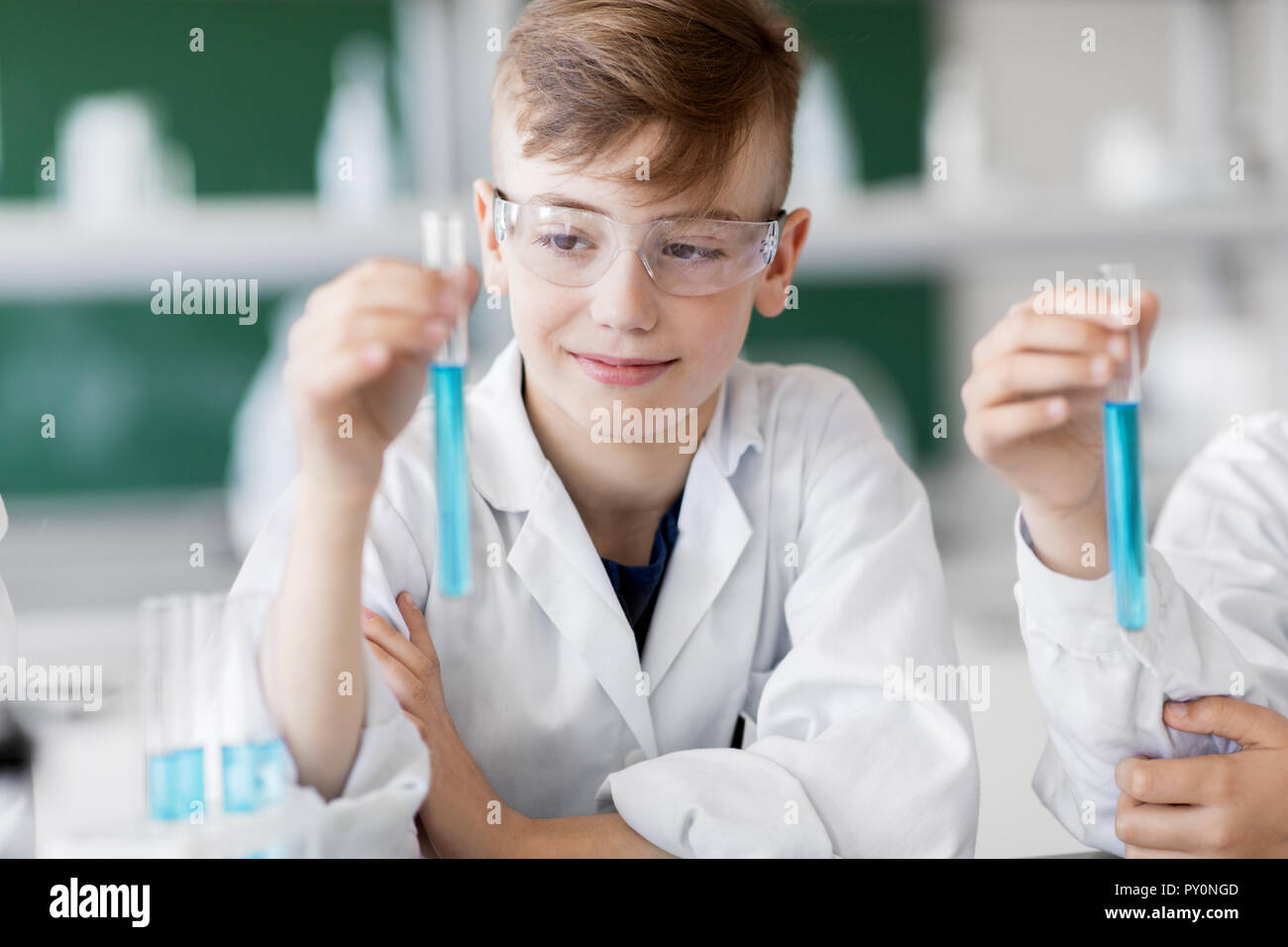 Ragazzo con tubo di prova che studia chimica a scuola Foto Stock