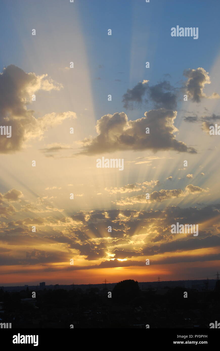 Raggi di sole che passa attraverso le nuvole contro un cielo blu Foto Stock