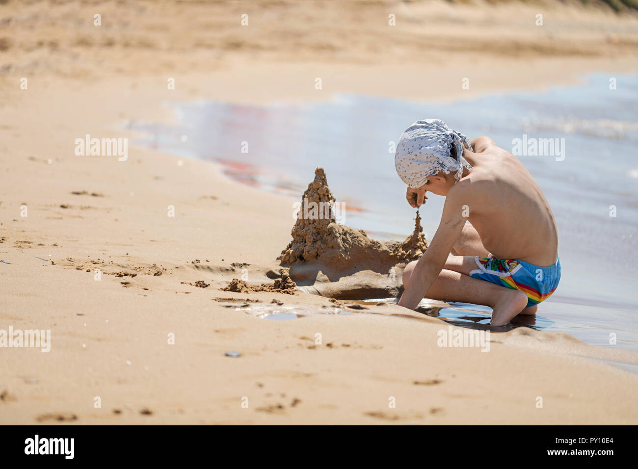 Ragazzo la costruzione di un castello di sabbia sulla spiaggia, Corfù, Grecia Foto Stock