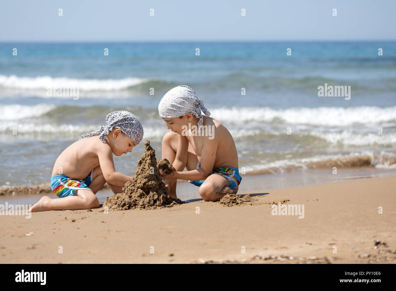 Due ragazzi di costruire un castello di sabbia sulla spiaggia, Corfù, Grecia Foto Stock