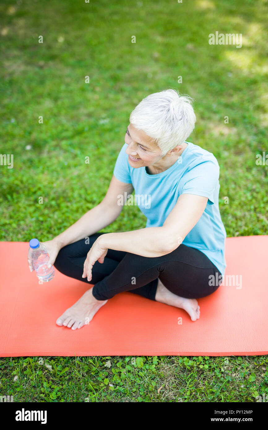 Senior donna seduta e riposo dopo allenamento nel parco Foto Stock