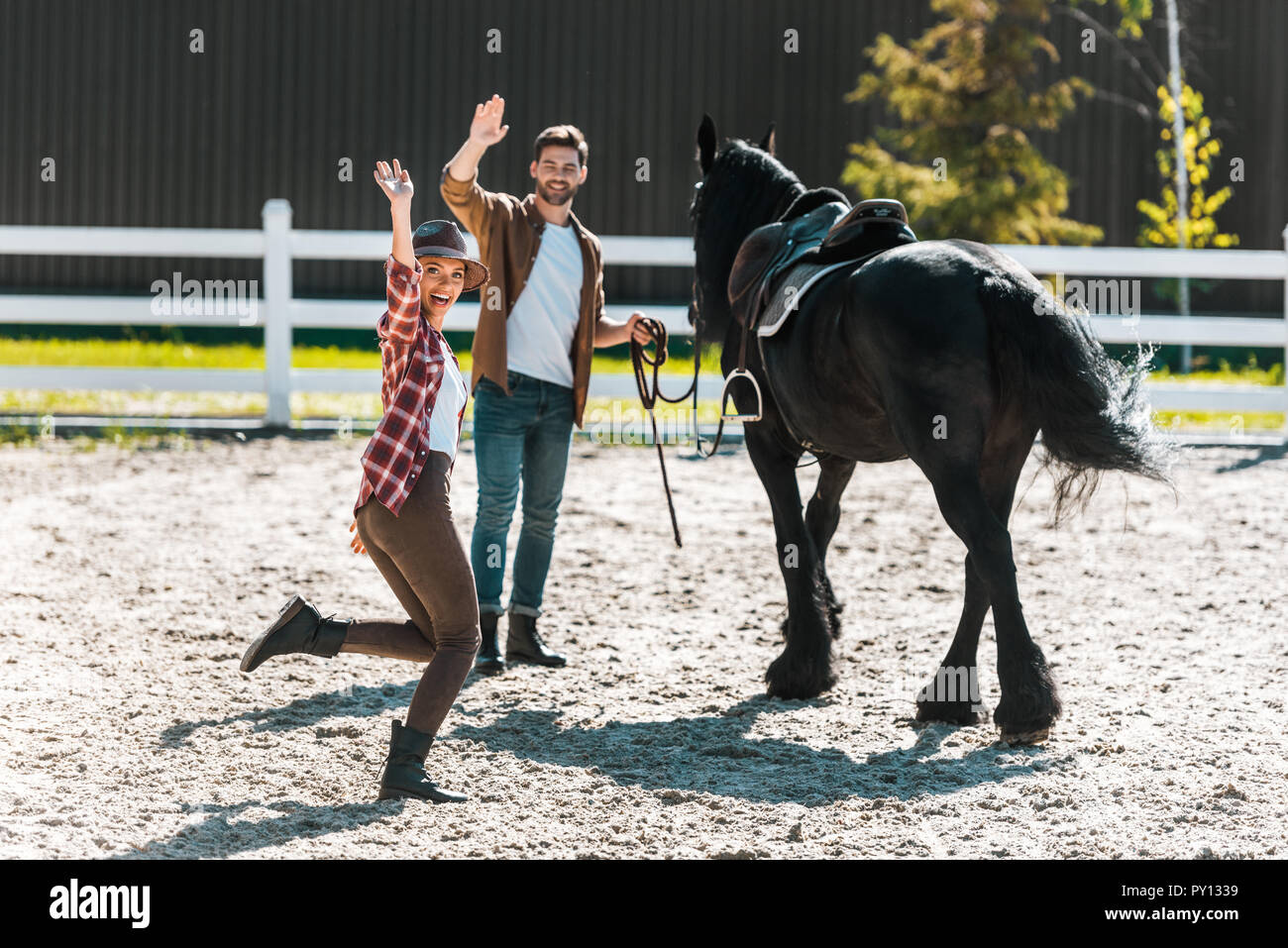 Felice di sesso maschile e femminile equestrians passeggiate a cavallo al  ranch e agitando le mani Foto stock - Alamy