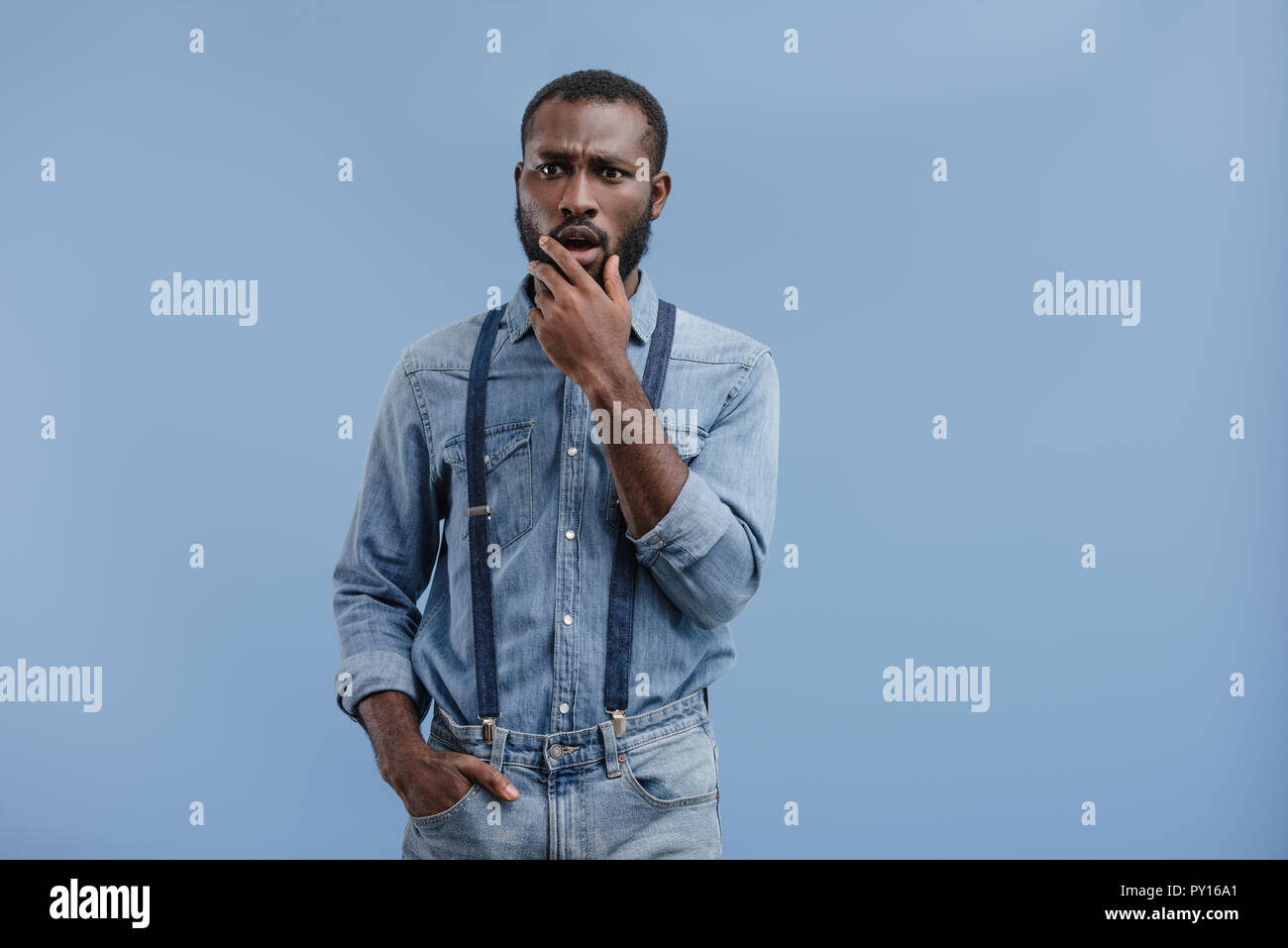 Scioccato African American uomo chiudendo la bocca con la mano isolato su sfondo blu Foto Stock