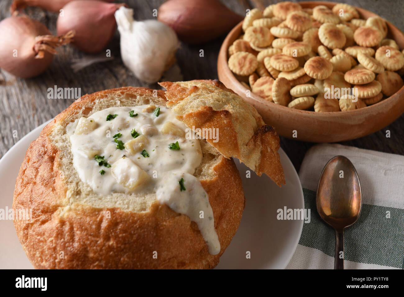 Primo piano della ciotola di pane del New England Clam Chowder. Una ciotola di oyster crackers, aglio e cipolle in background. Foto Stock