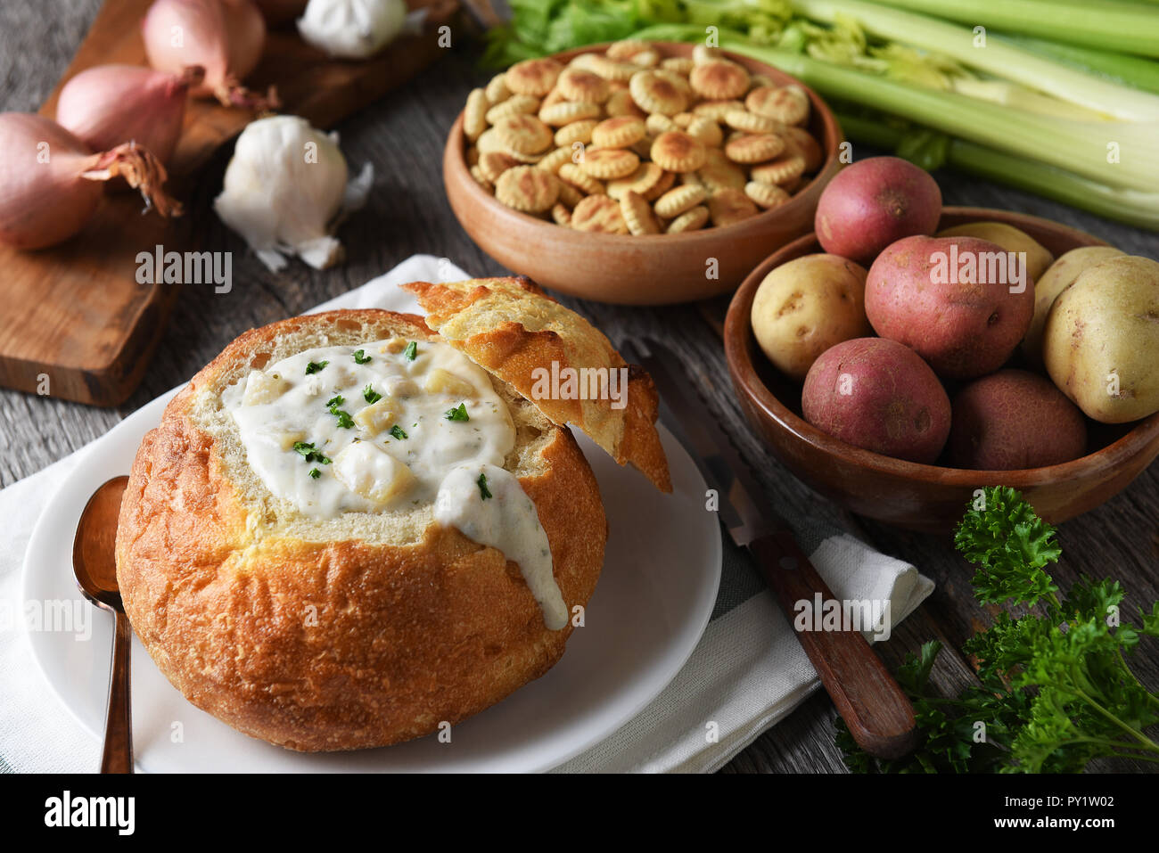 New England Clam Chowder: ciotola di pane pieno di freschi fatti in casa con zuppa di cracker e ingredienti. Foto Stock