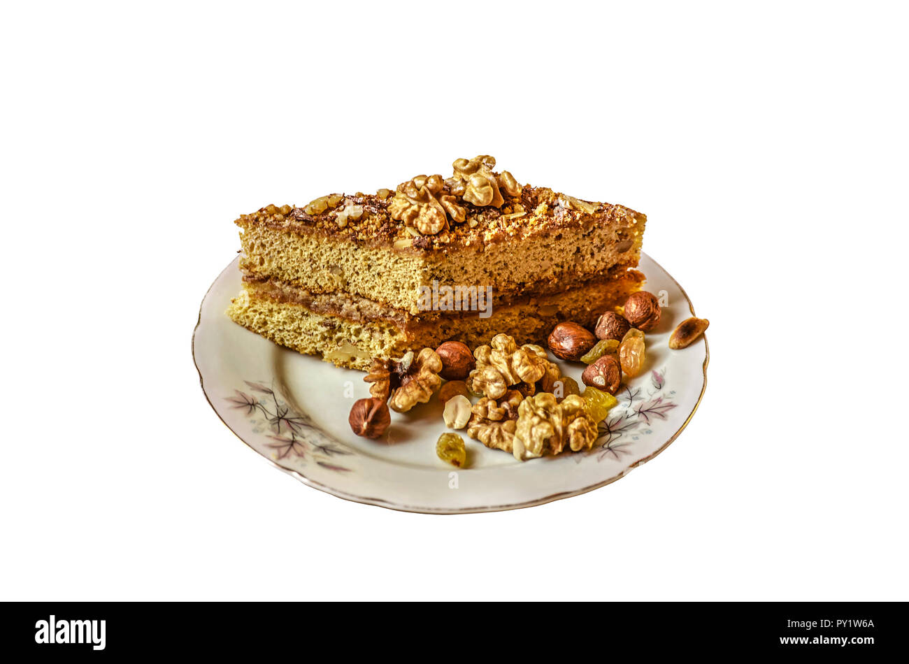 Pezzo di torta di miele con dadi su una piastra di porcellana con uvetta,nocciole, noci e noccioline su sfondo bianco Foto Stock