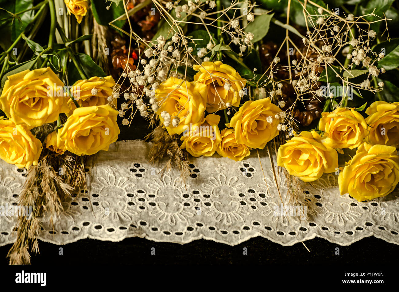 Bianco bordo ricamato con rose giallo,rami secchi di bianco hypsophila e ance su sfondo nero Foto Stock
