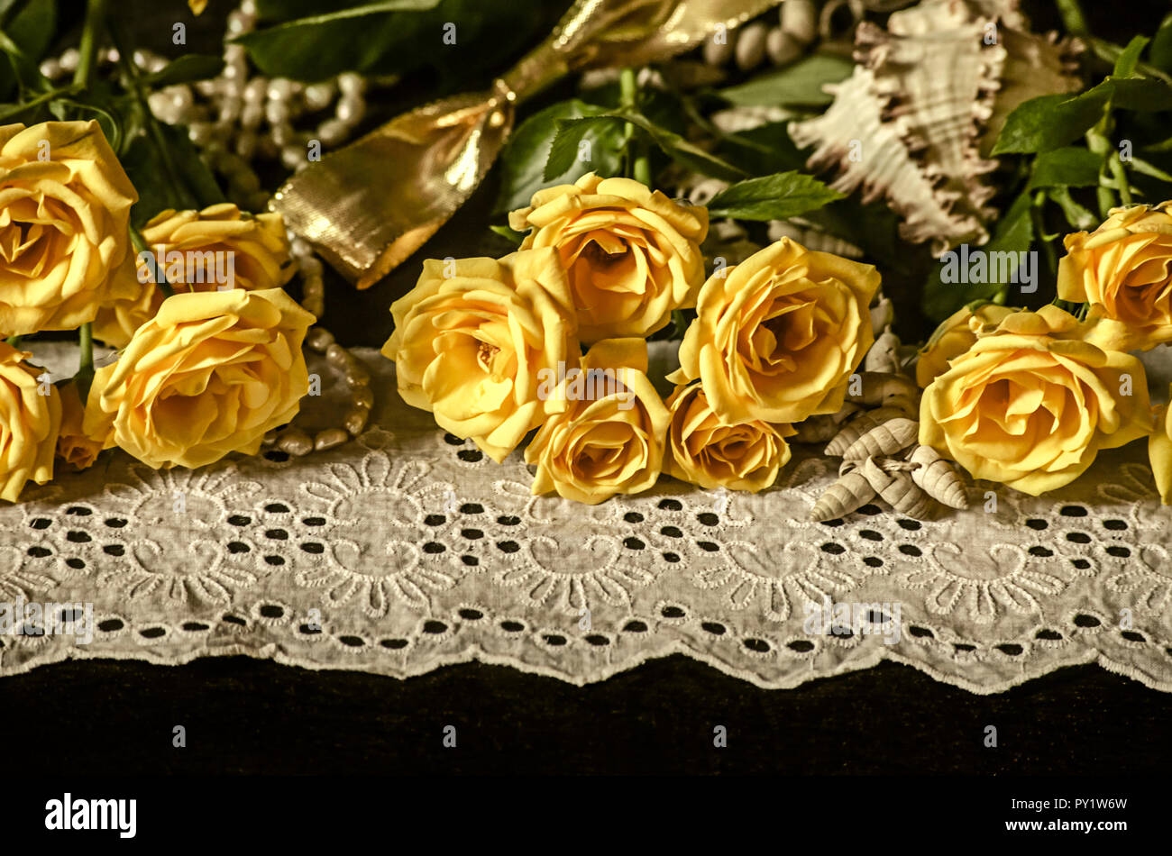 Ciuffi con giallo rose, rami secchi di bianco gypsophila,ance su un bianco bordo in pizzo con perle perle, conchiglie e golden nastro su una parte posteriore in nero Foto Stock