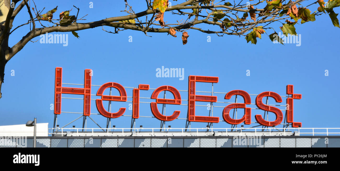 Rosso segno HereEast sul tetto di qui est conversione di Olimpiadi di edificio di media a Hackney Wick in uffici studios retail & innovazione spazi London REGNO UNITO Foto Stock