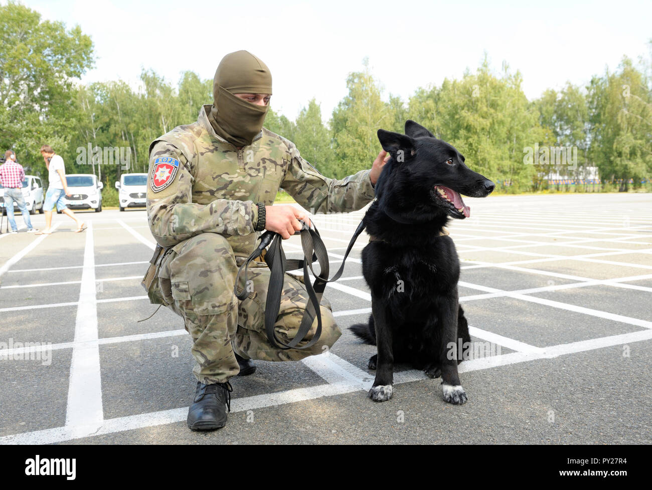 Soldato di unità di KORD (Ucraino SWAT) in uniforme e il suo cane poliziotto seduto su un terreno. Il 5 settembre 2018. A Kiev, Ucraina Foto Stock