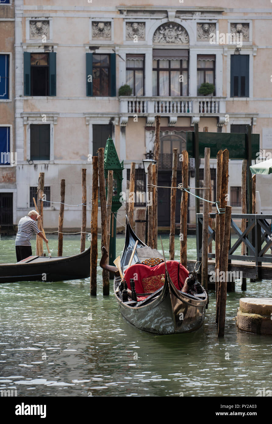 Un traghetto, uno dei traghetti tradizionali attraverso il Grand Canal è uscire da un molo. In primo piano una gondola è ormeggiata al pontile stesso. Foto Stock