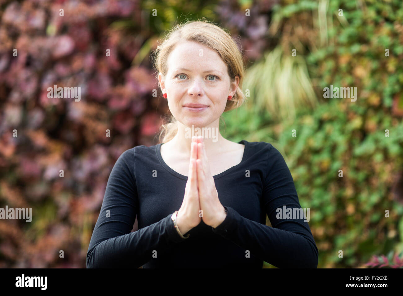 Ritratto di una donna in piedi nel parco con le mani in posizione di preghiera Foto Stock