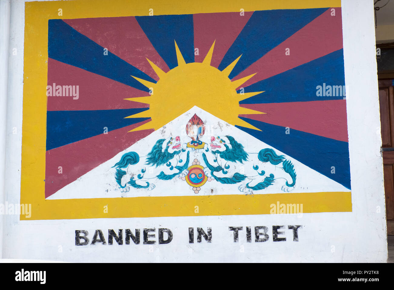 Bandiera tibetana dipinta sulla parete con slogan 'vietato in Tibet", Dharamshala, India Foto Stock