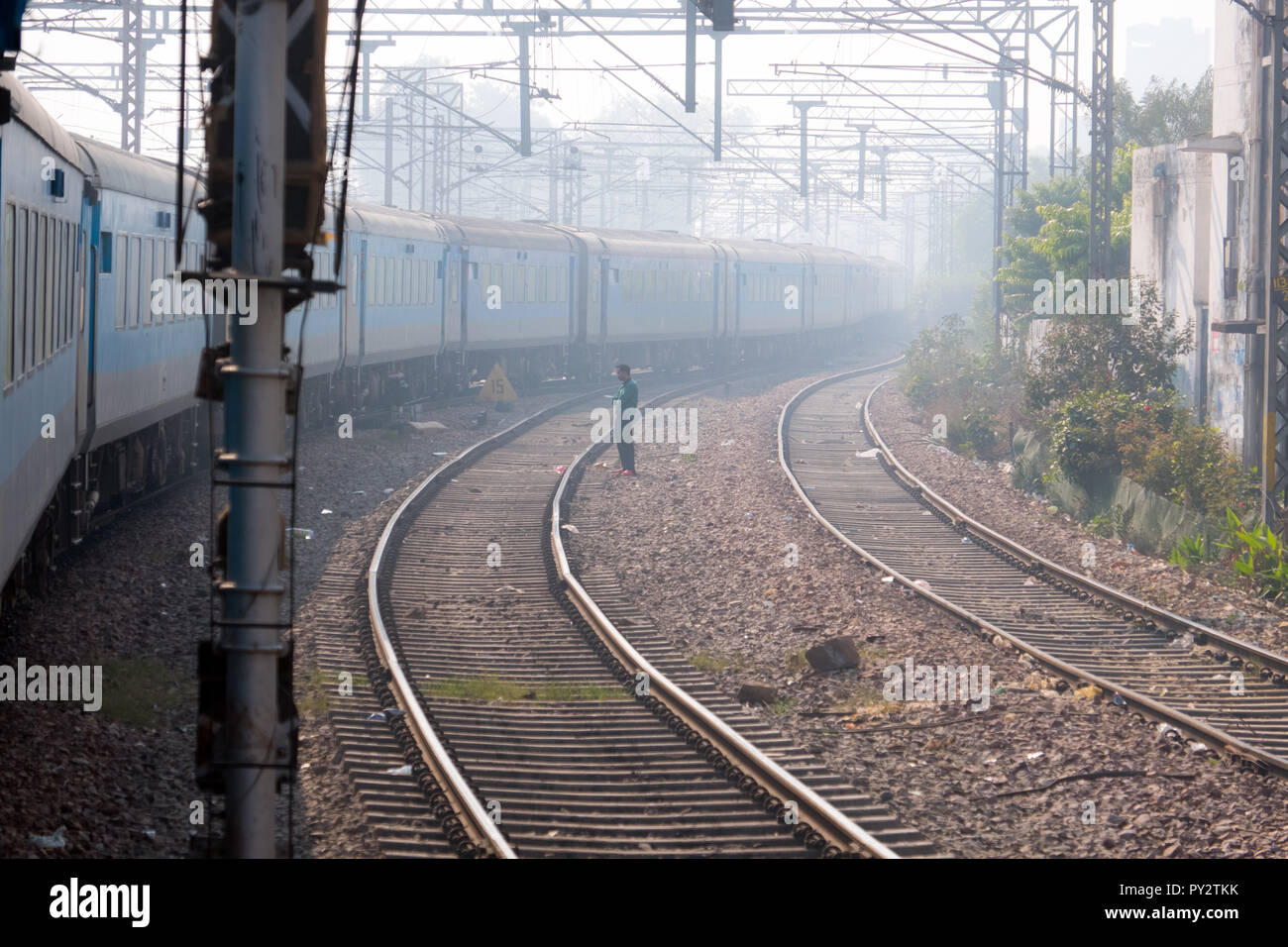 Indian Treno in avvicinamento a Delhi stazione ferroviaria di mattina presto haze Foto Stock