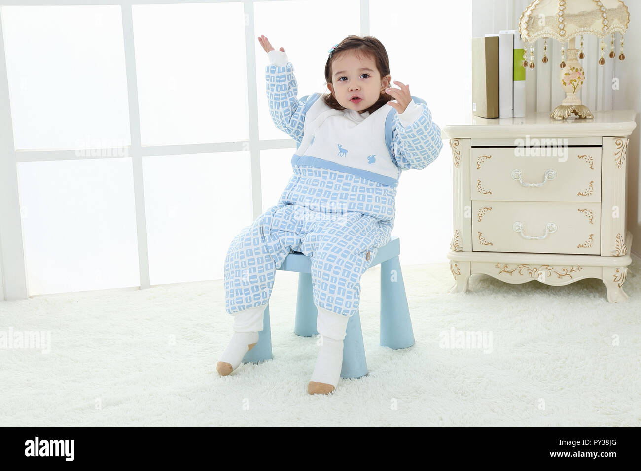La bambina in un vestito blu vicino a una finestra. Ritratto della bambina. Abito della principessa Foto Stock