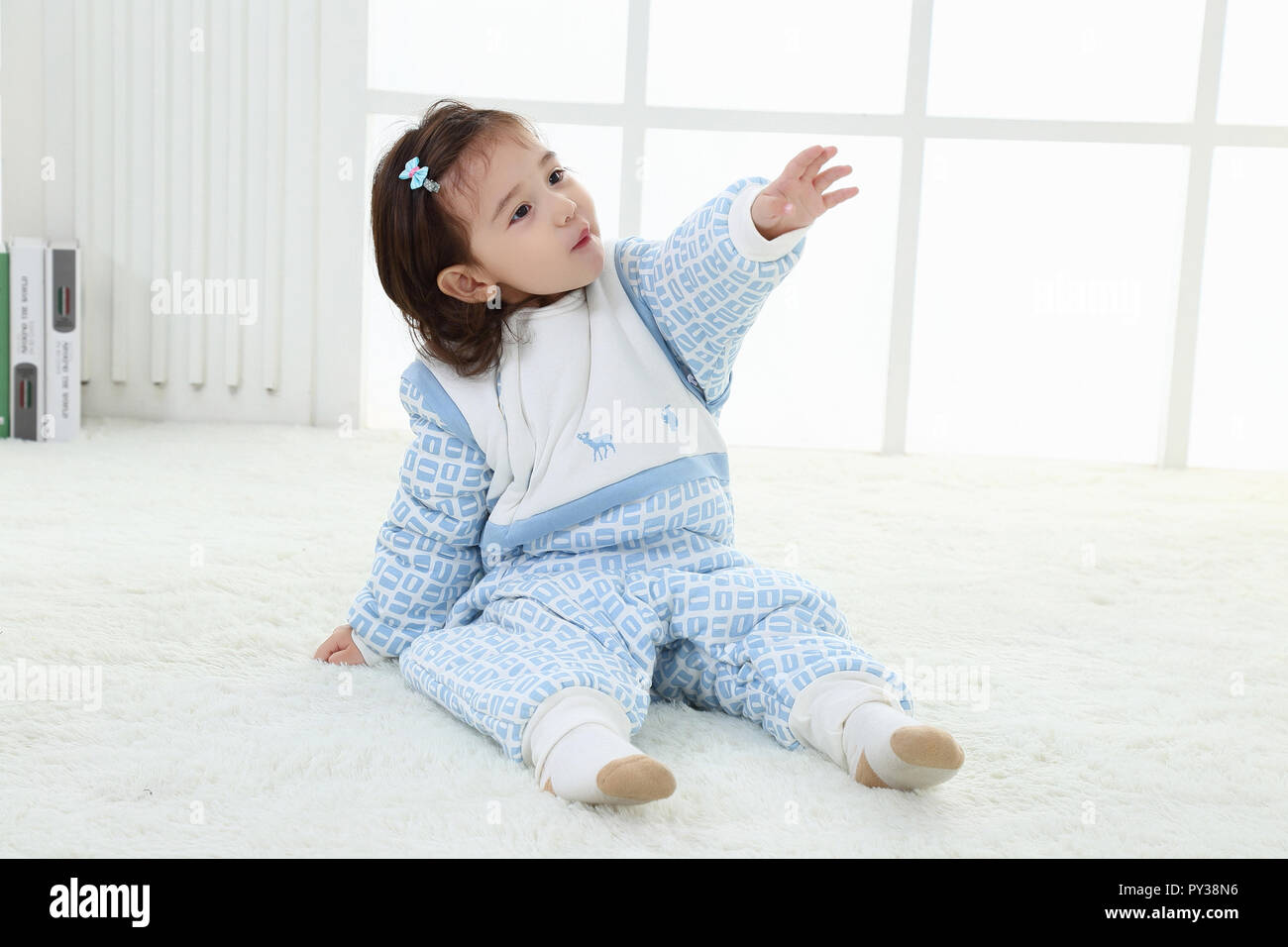 La bambina in un vestito blu vicino a una finestra. Ritratto della bambina. Abito della principessa Foto Stock