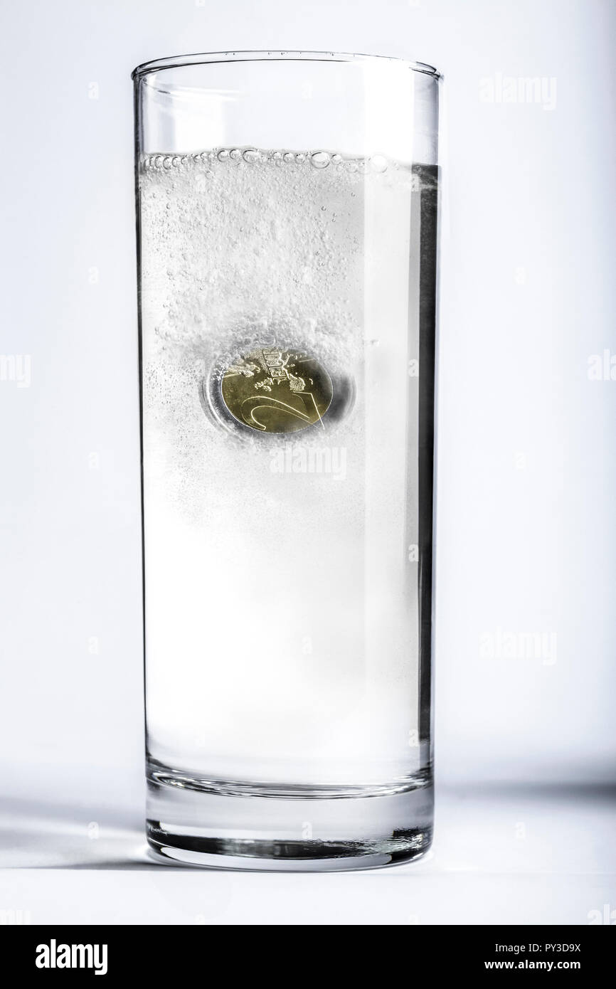 Euro Muenze loest sich in Wasserglas auf Foto Stock