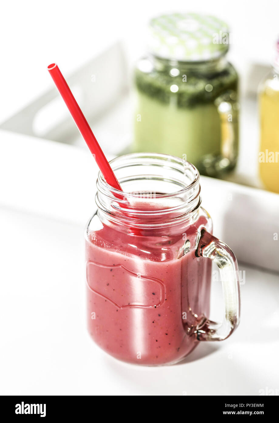 Erdbeersmoothie im Vordergrund, gruener und gelber Smoothie im Hintergrund Foto Stock