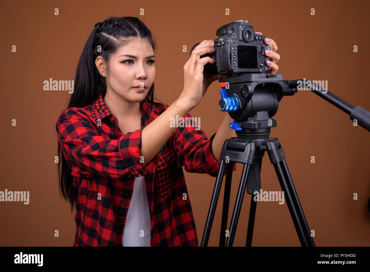 Giovane donna asiatica fotografo regolare la fotocamera sul cavalletto Foto Stock