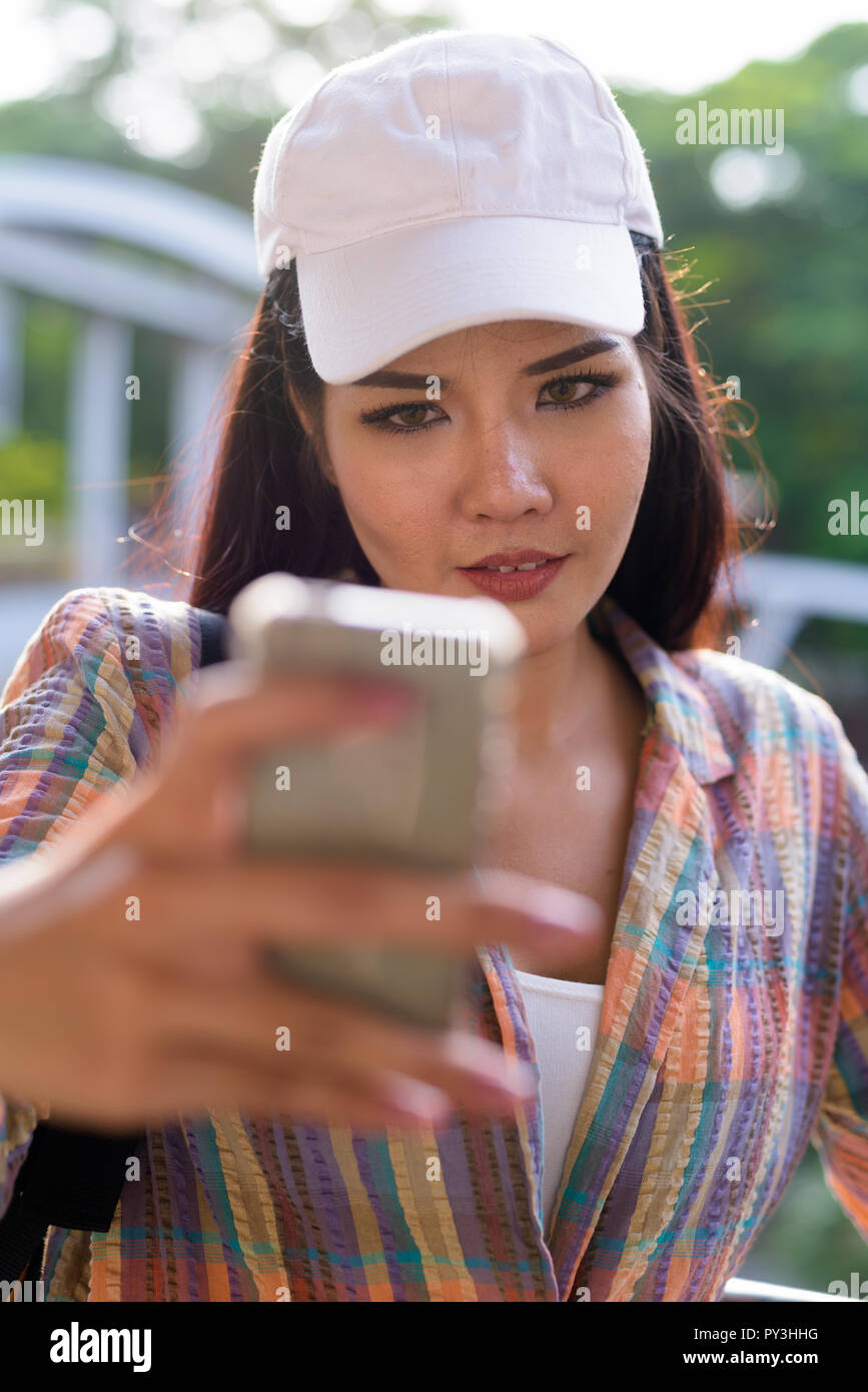 Giovane bella donna asiatica utilizzando il telefono cellulare all'aperto Foto Stock