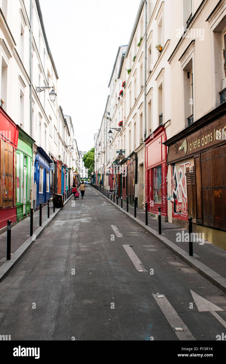 Strada stretta e luminosa di negozi colorati e negozi quasi vuoti di persone e non riconoscibili in lontananza, a Belleville, Parigi, Francia Foto Stock