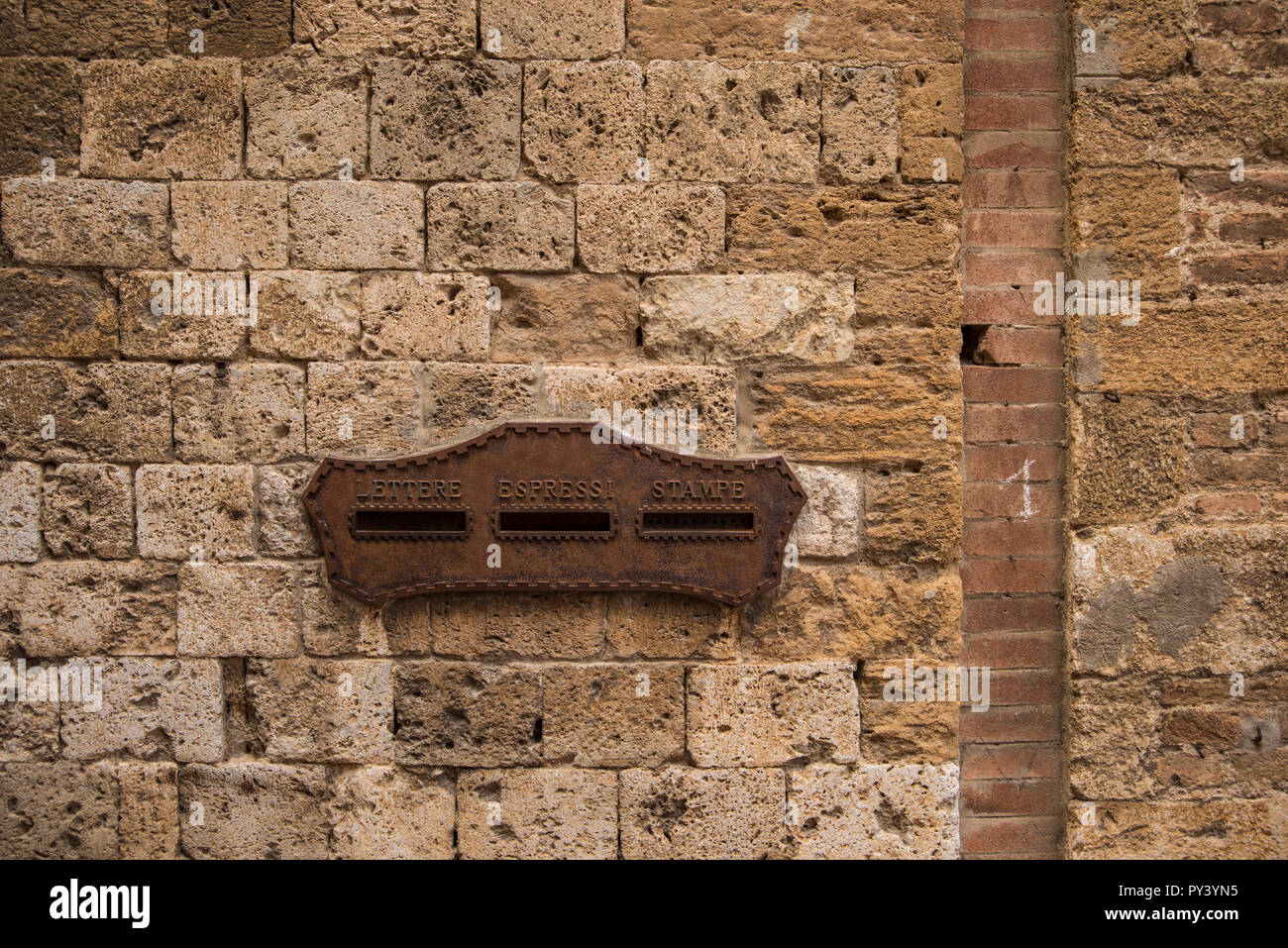 Vecchio metallo ornati Caselle lettera sul muro di pietra, cittadina collinare di San Gimignano, Toscana, Italia Foto Stock