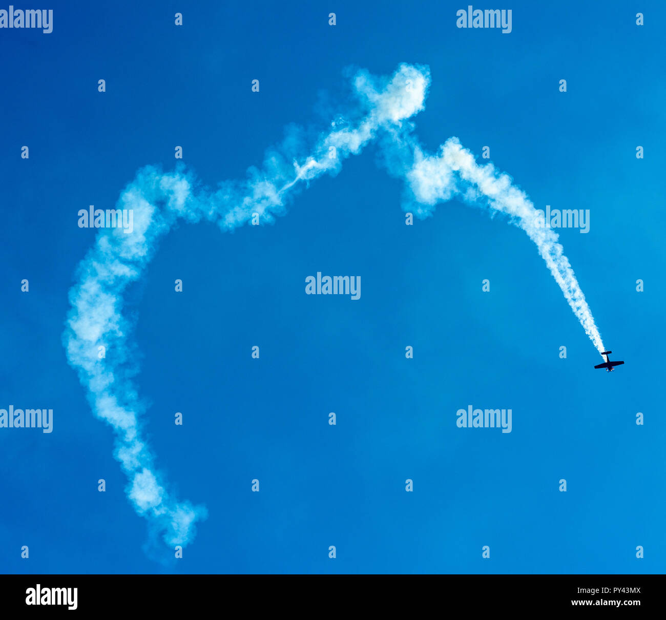 Il pilota di acrobazie esegue manovre audaci in uno spettacolo aereo in Francia con vivaci sentieri per il fumo Foto Stock