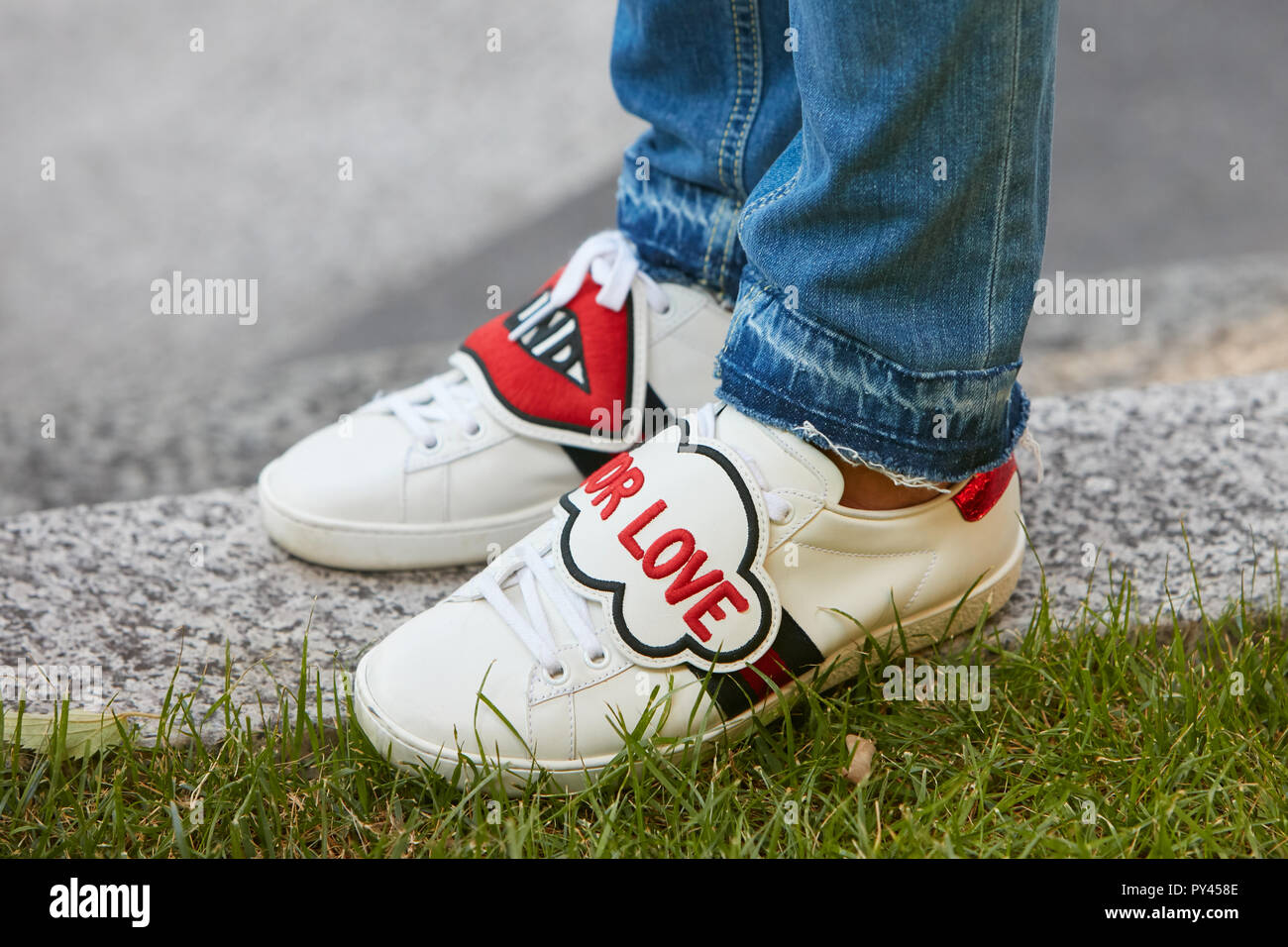 Milano, Italia - 23 settembre 2018: Donna con Gucci scarpe bianco "cieco  per amore" e blu denim pantaloni prima di Giorgio Armani fashion show,  Milano Fas Foto stock - Alamy