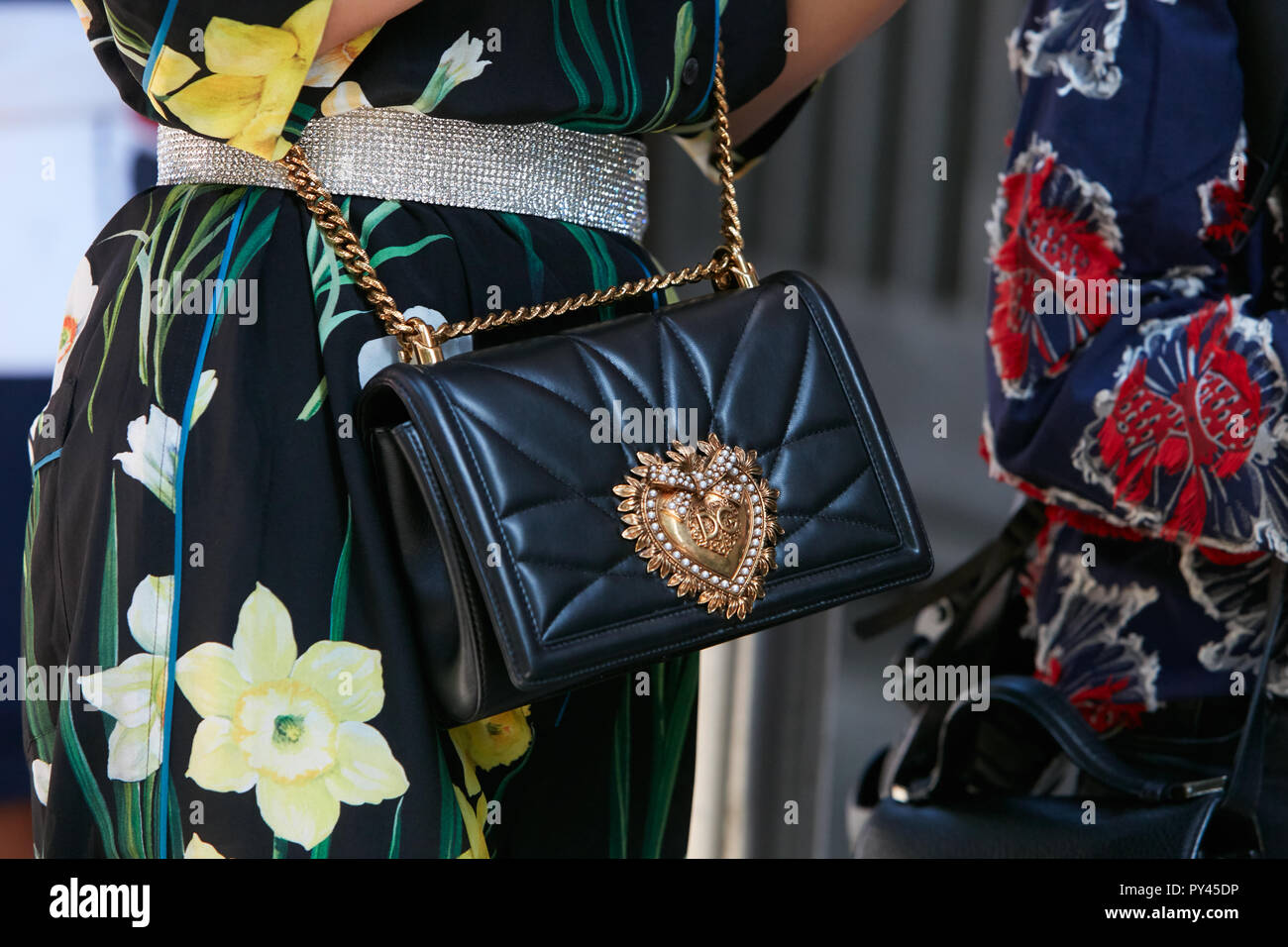 Milano, Italia - 23 settembre 2018: donna in pelle nera di Dolce e Gabbana borsa con cuore d'oro e abito nero con fiori di colore giallo prima di Giorgio Foto Stock